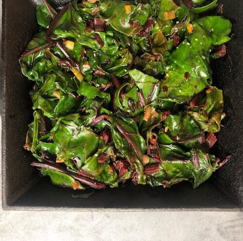 Overhead view of sautéed beet greens in cast iron pan