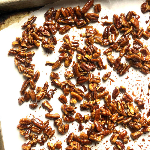 Candied pecans on parchment paper and baking sheet