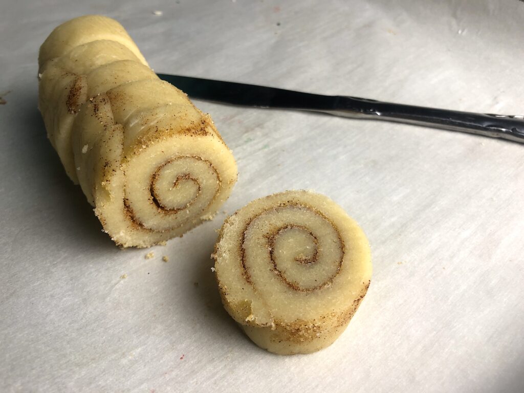 log of cinnamon roll dough with butter knife