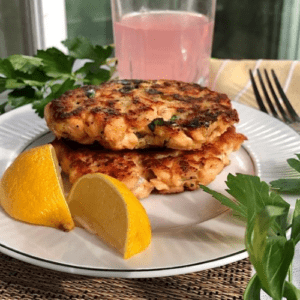 Two salmon cakes made with fresh salmon with lemon wedges