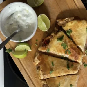 Salmon fajita quesadillas on a cutting board with dipping sauce