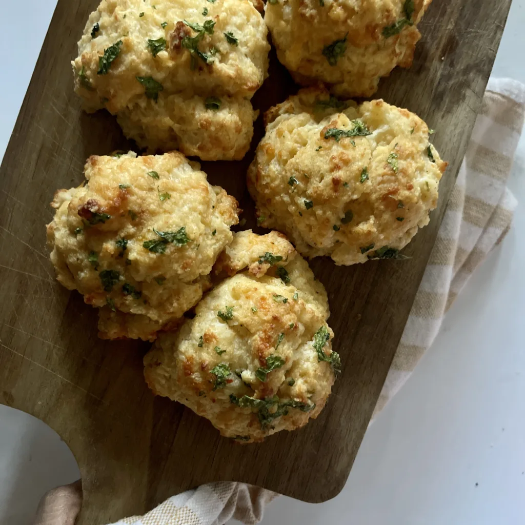 homemade cheddar bay biscuits on a wooden cutting board and white countertop