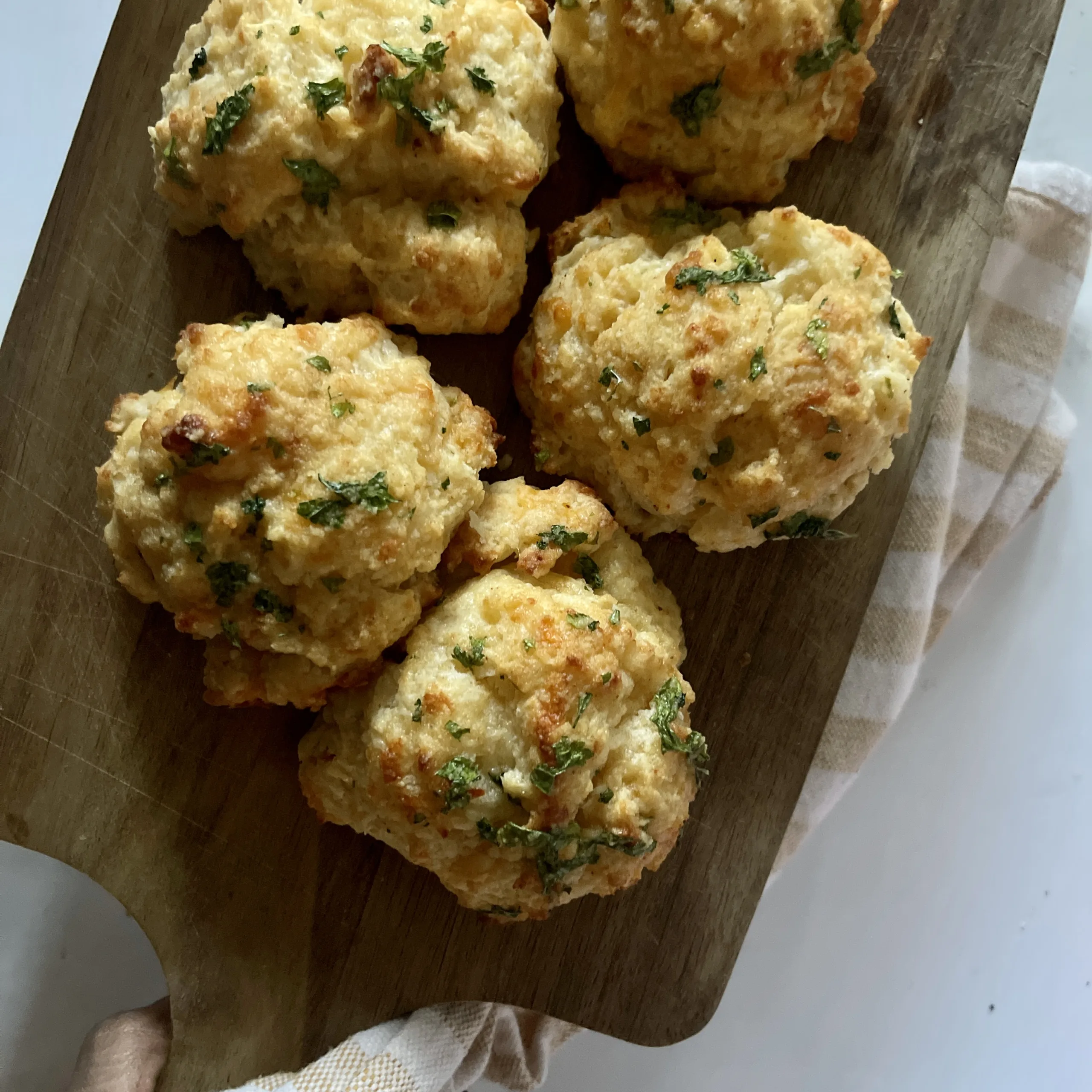homemade cheddar bay biscuits on a wooden cutting board and white countertop