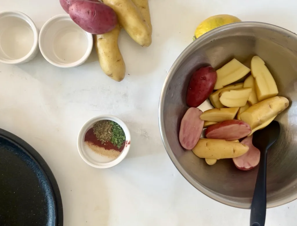 fingerling potatoes halved in a mixing bowl with seasonings
