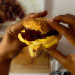 two hands holding bacon egg and cheese biscuit
