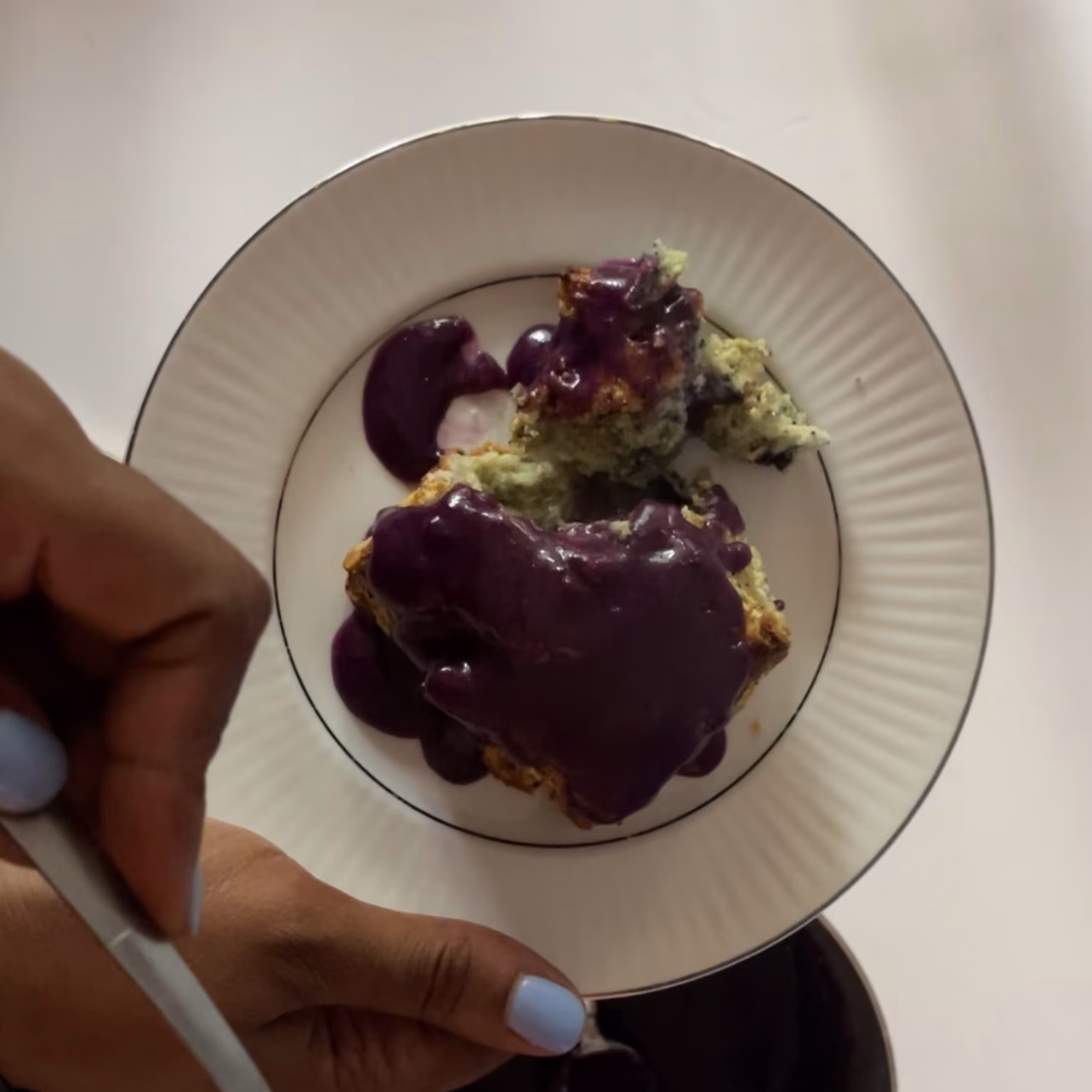 overhead picture of blueberry biscuit with a corner crumbling off to the top of the plate