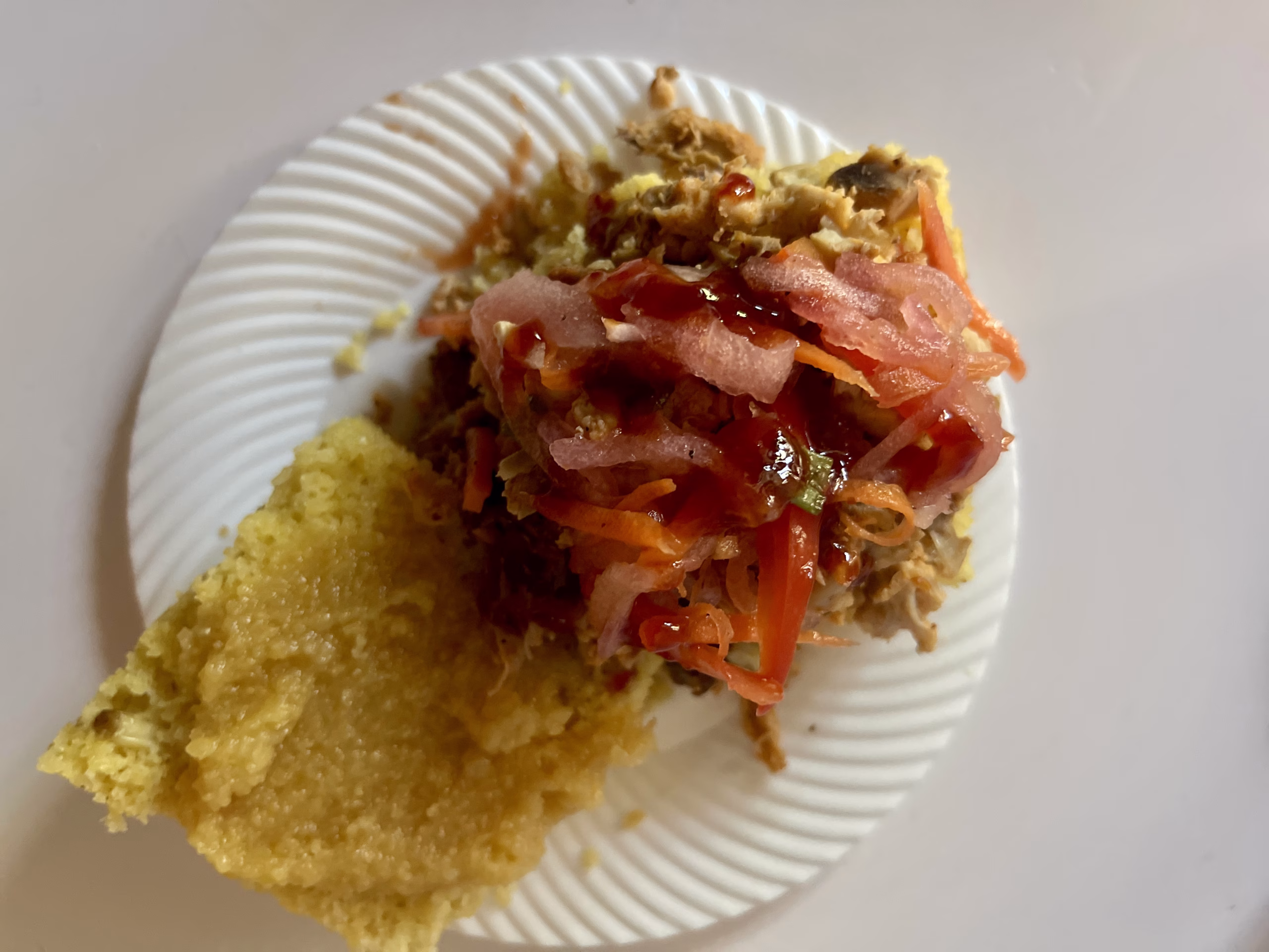 an open face cornbread biscuit with smoked chicken watermelon bbq sauce and watermelon rind relish on a small white plate